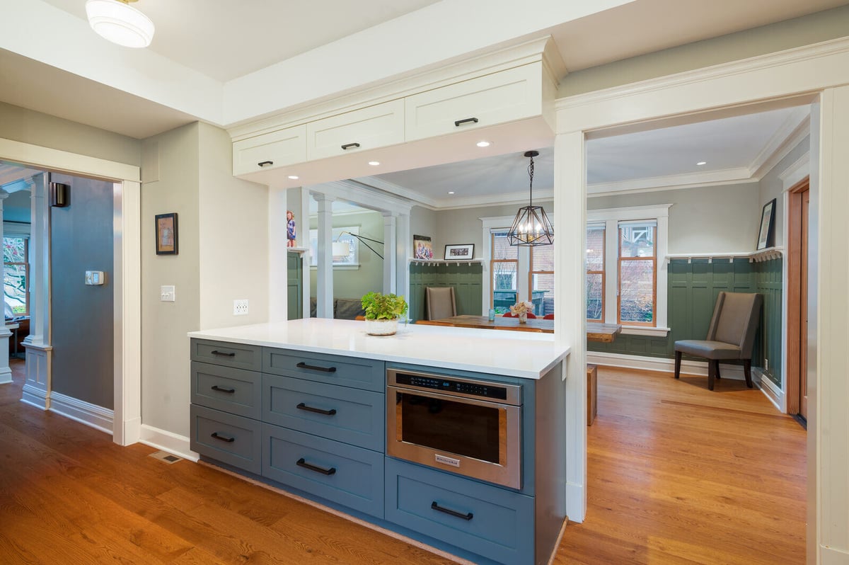 Open-concept kitchen with custom cabinetry by CB Construction, featuring blue lower cabinets and a white countertop in a Seattle remodel