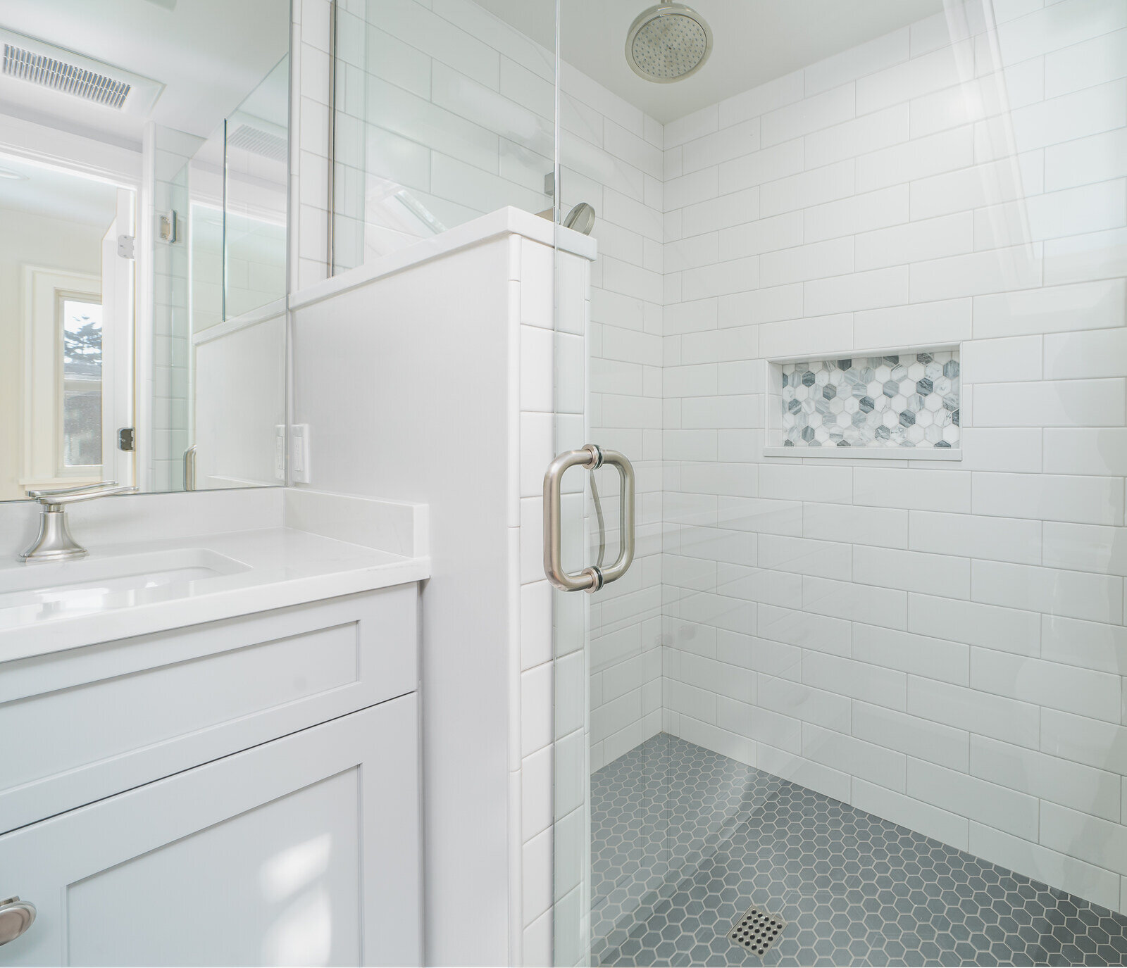 Glass-enclosed shower with white subway tile and niche in a Seattle bathroom, remodeled by CB Construction