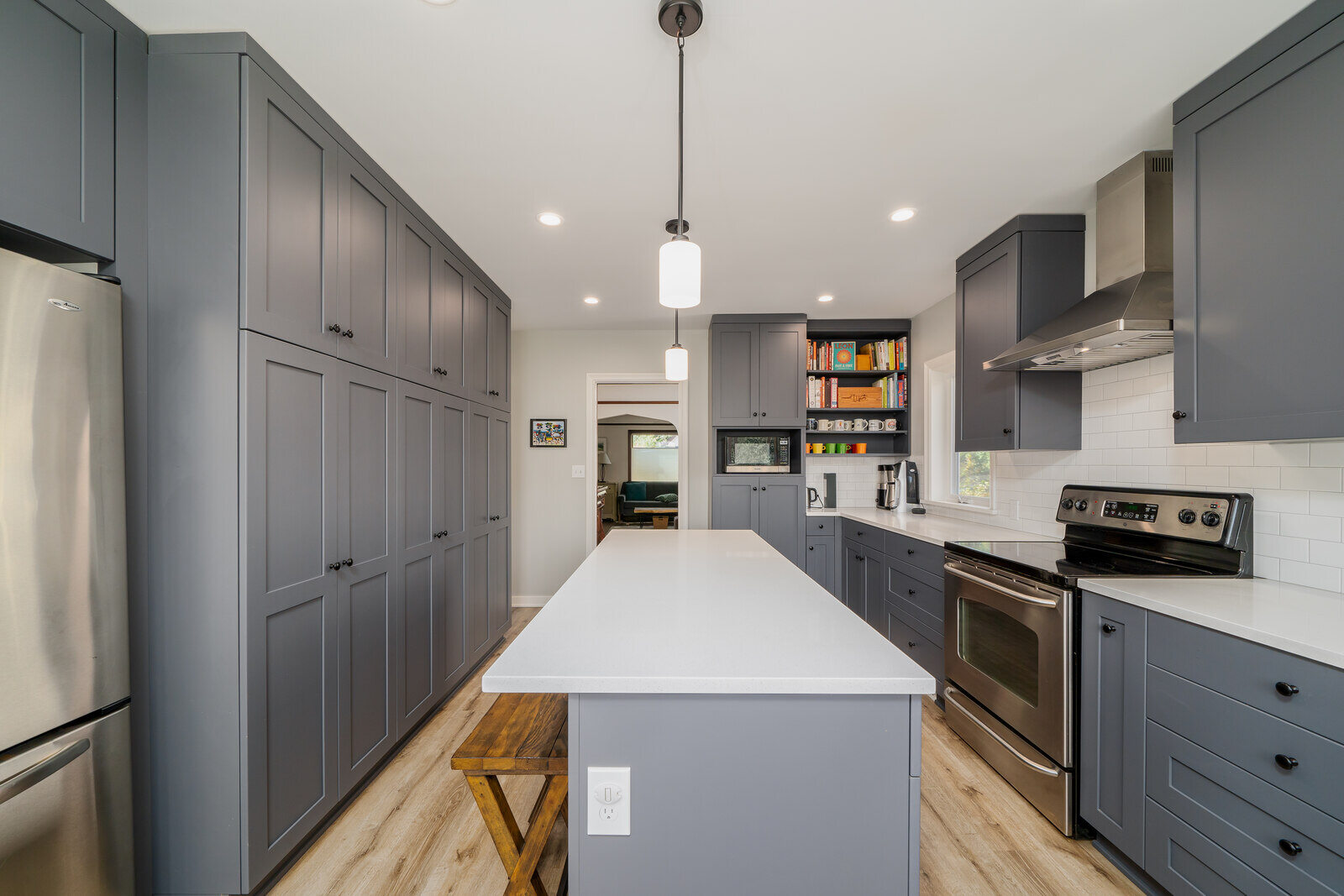 Modern kitchen by CB Construction in Seattle featuring grey cabinetry, stainless steel appliances, and a white quartz countertop island