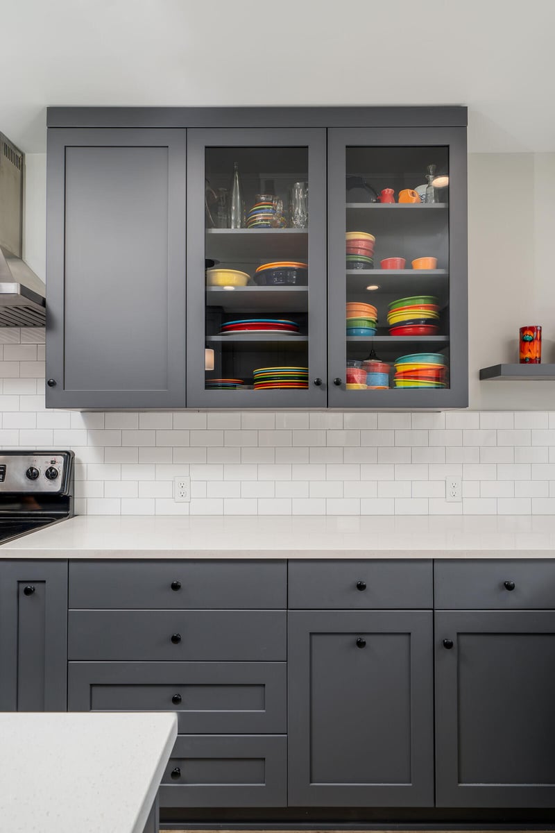 Modern kitchen in Seattle by CB Construction with grey cabinetry and open shelves displaying colorful dishware