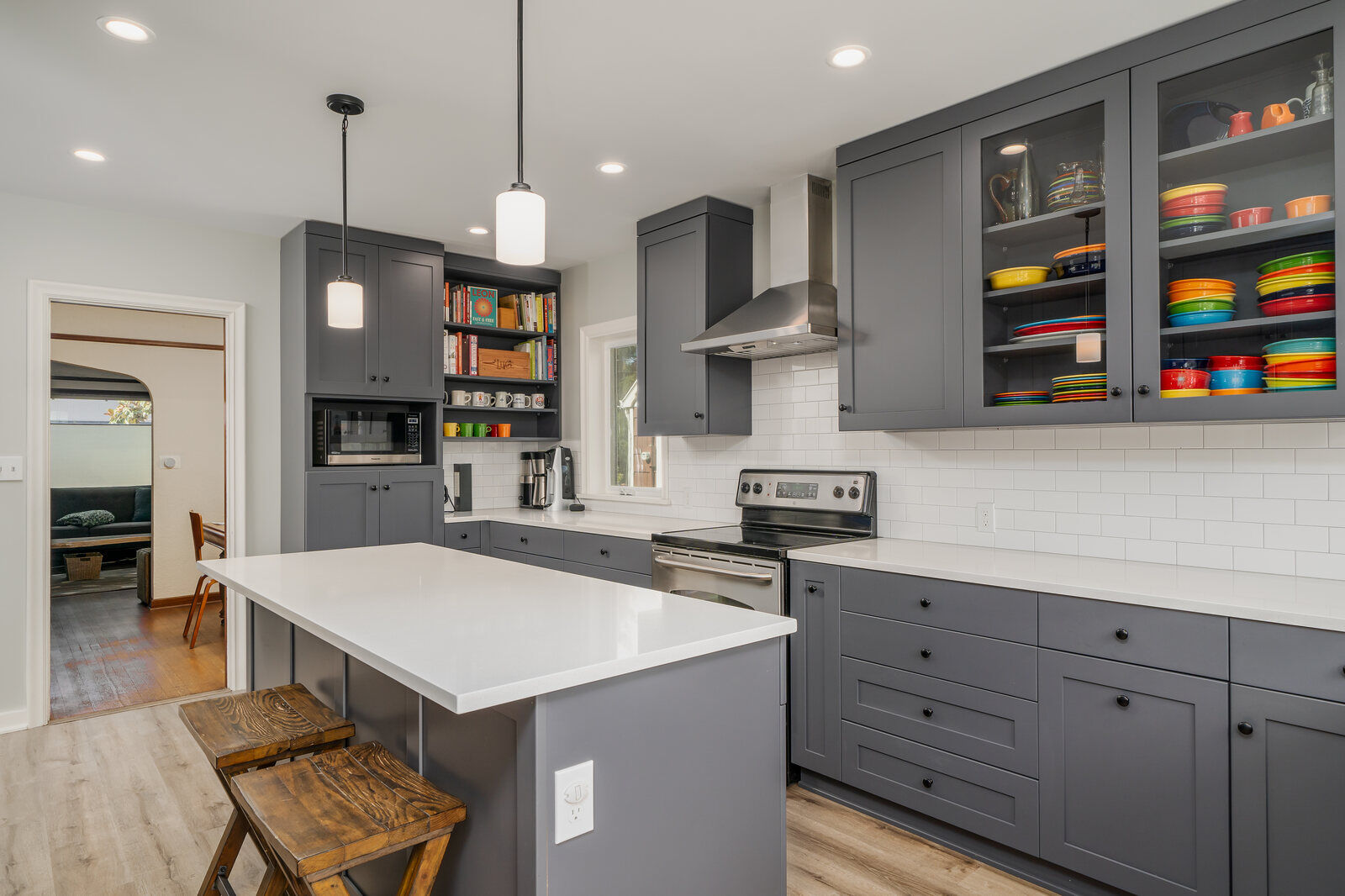 Modern kitchen remodel in Seattle by CB Construction featuring grey cabinetry, white quartz countertops, and a large island with wood stools