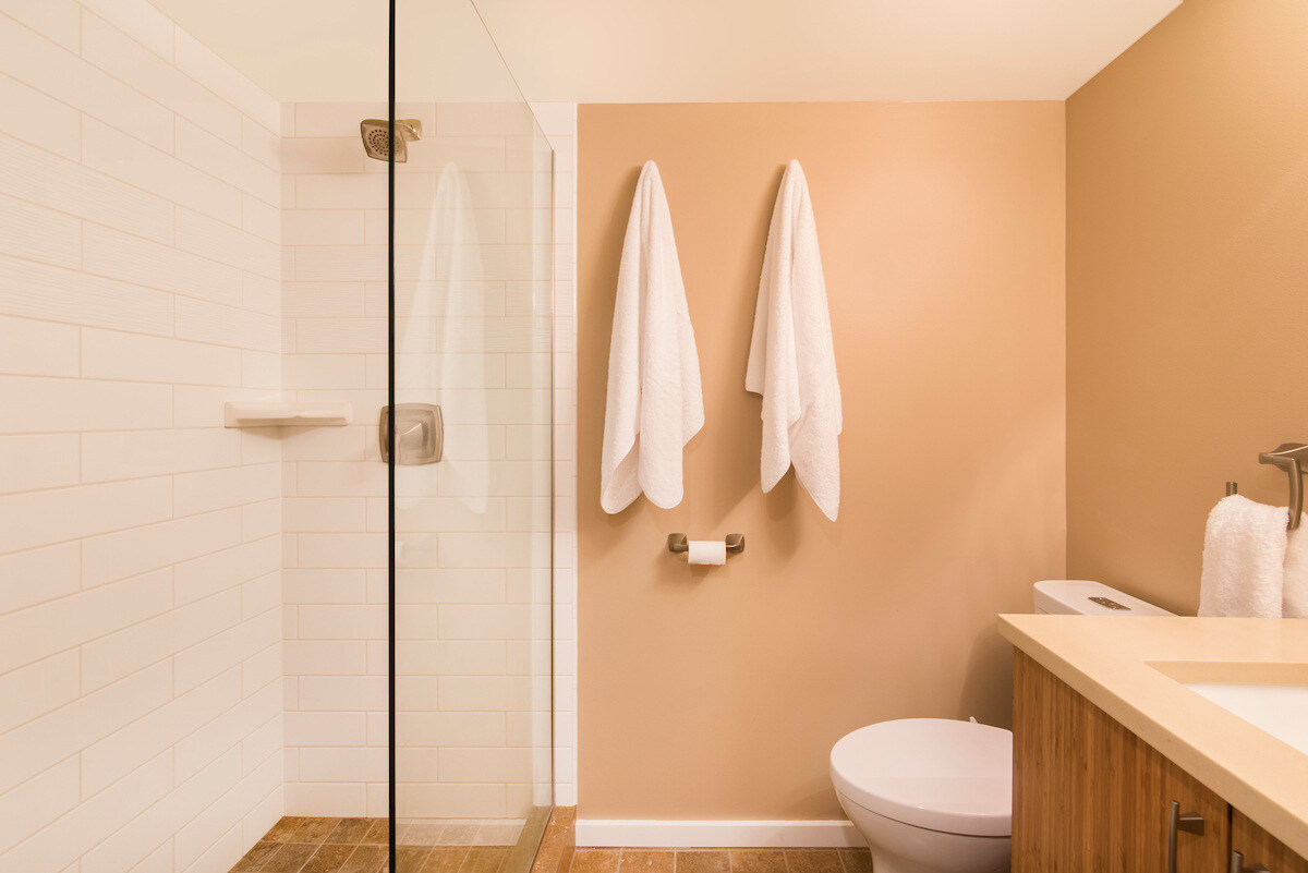 Modern bathroom in a Seattle basement Airbnb remodeled by CB Construction featuring glass shower and warm tones