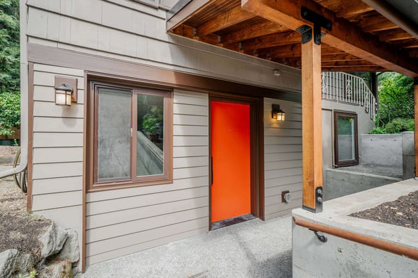 Exterior entrance to a Seattle basement ADU with an orange door, remodeled by CB Construction