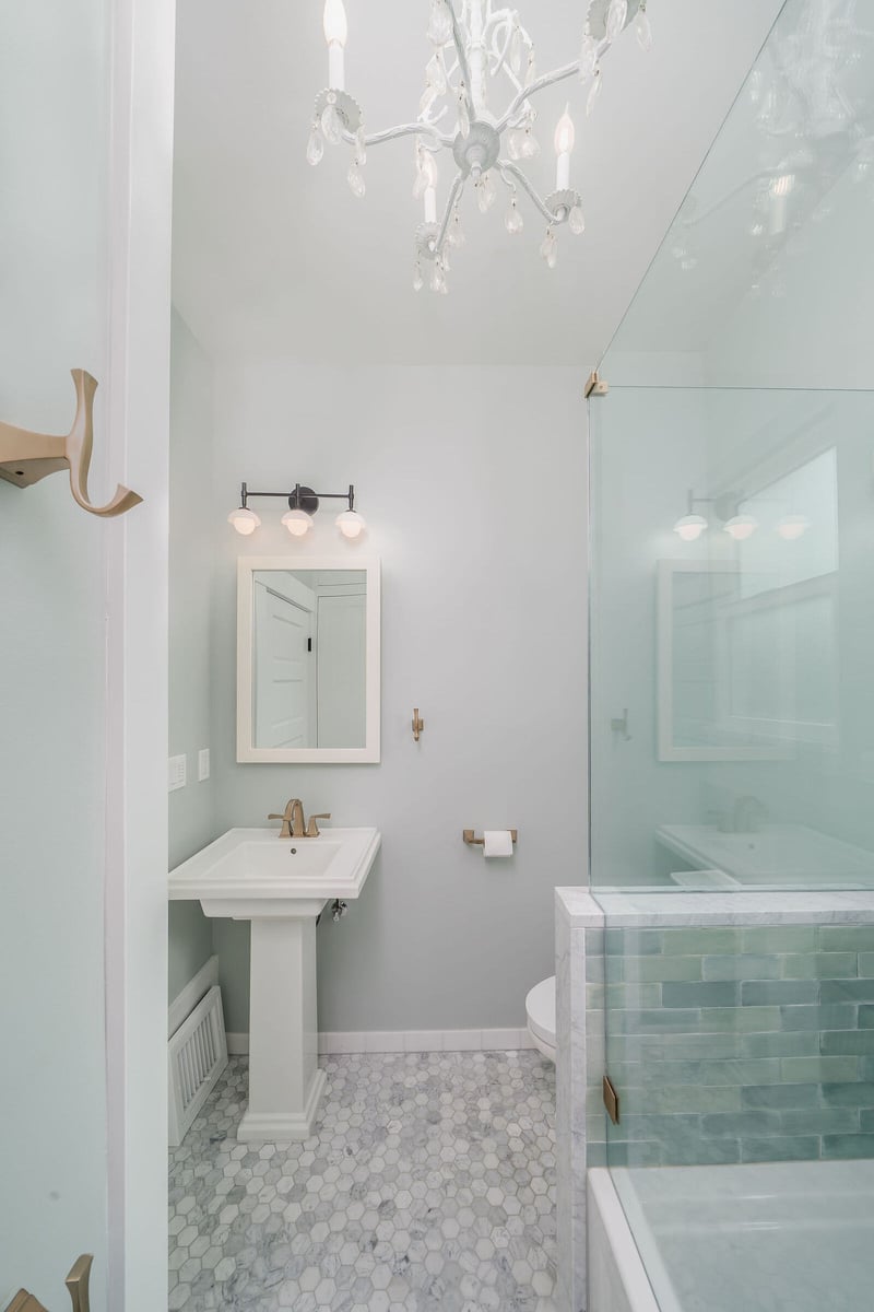Glass shower door with brass handles and green tile in a bathroom remodel by CB Construction in Seattle