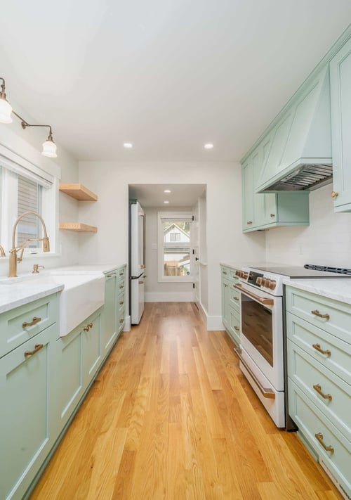 Spacious kitchen remodel with light green cabinets and hardwood floors in Seattle by CB Construction-1