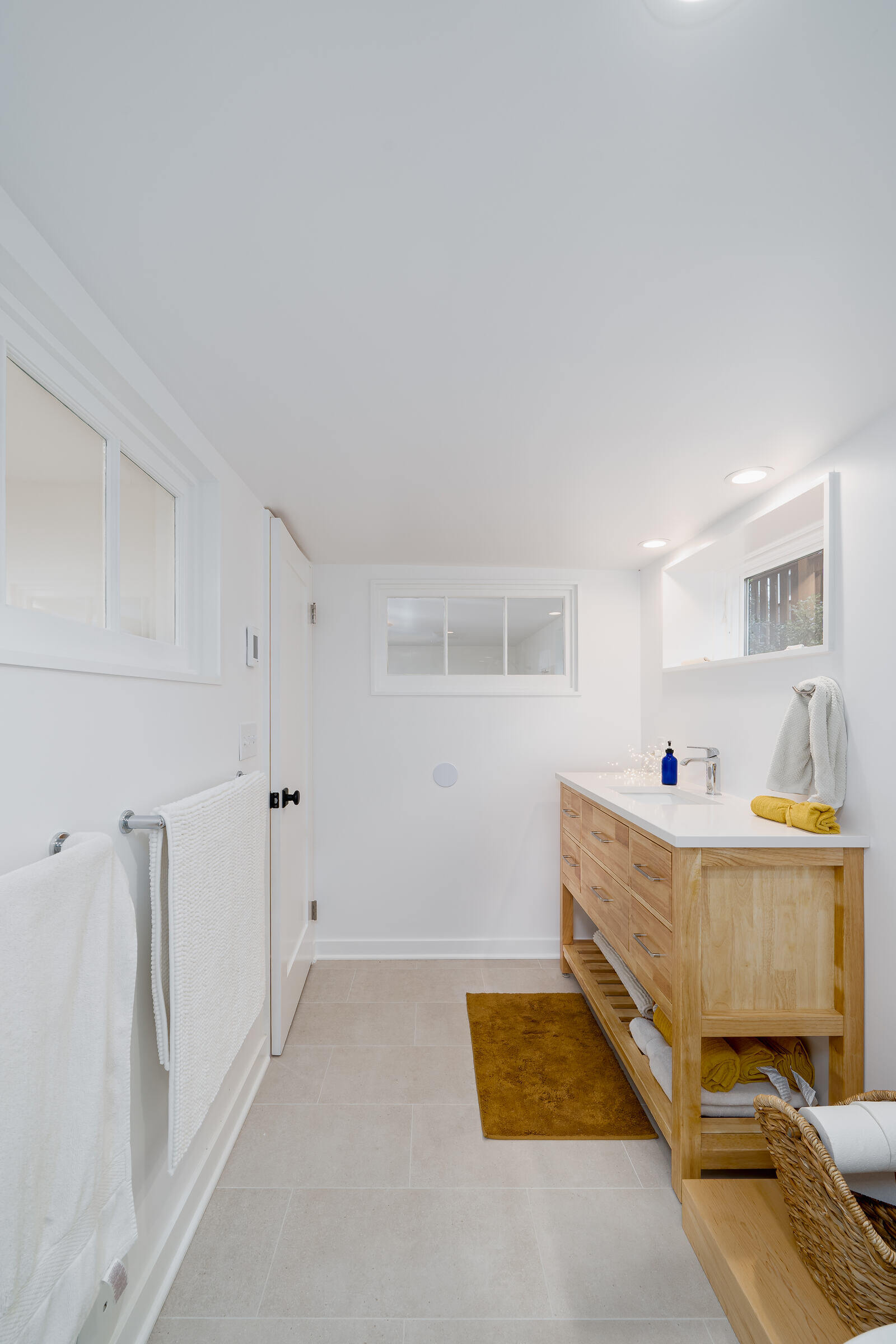 Light-filled, modern bathroom with wooden vanity in a Seattle basement remodel by CB Construction